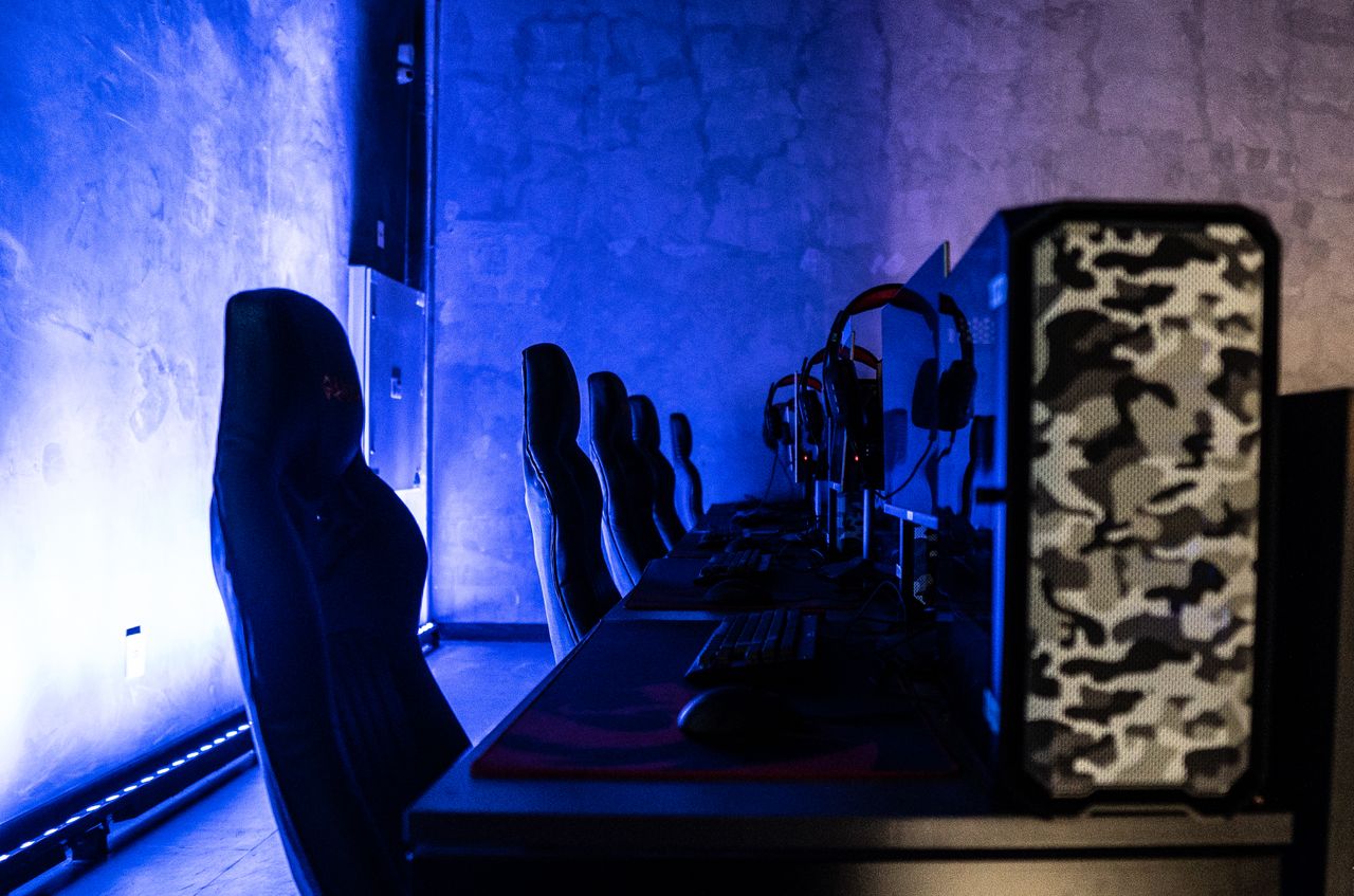青い照明の室内にゲーミングPCとチェアが並ぶeスポーツスペース