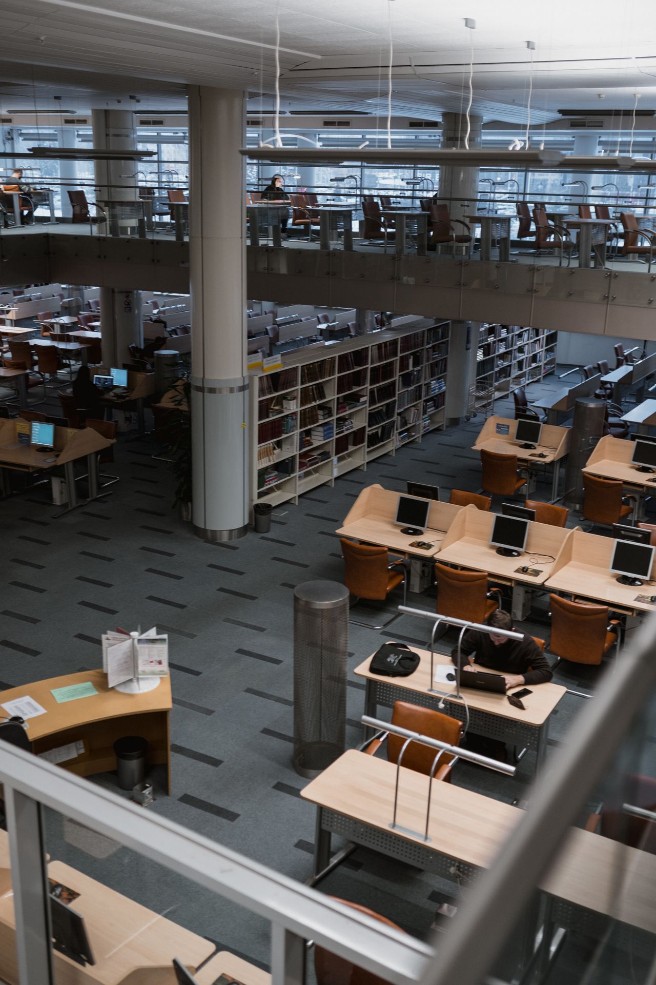 書架のそばに共用PCと閲覧席を備えた図書館