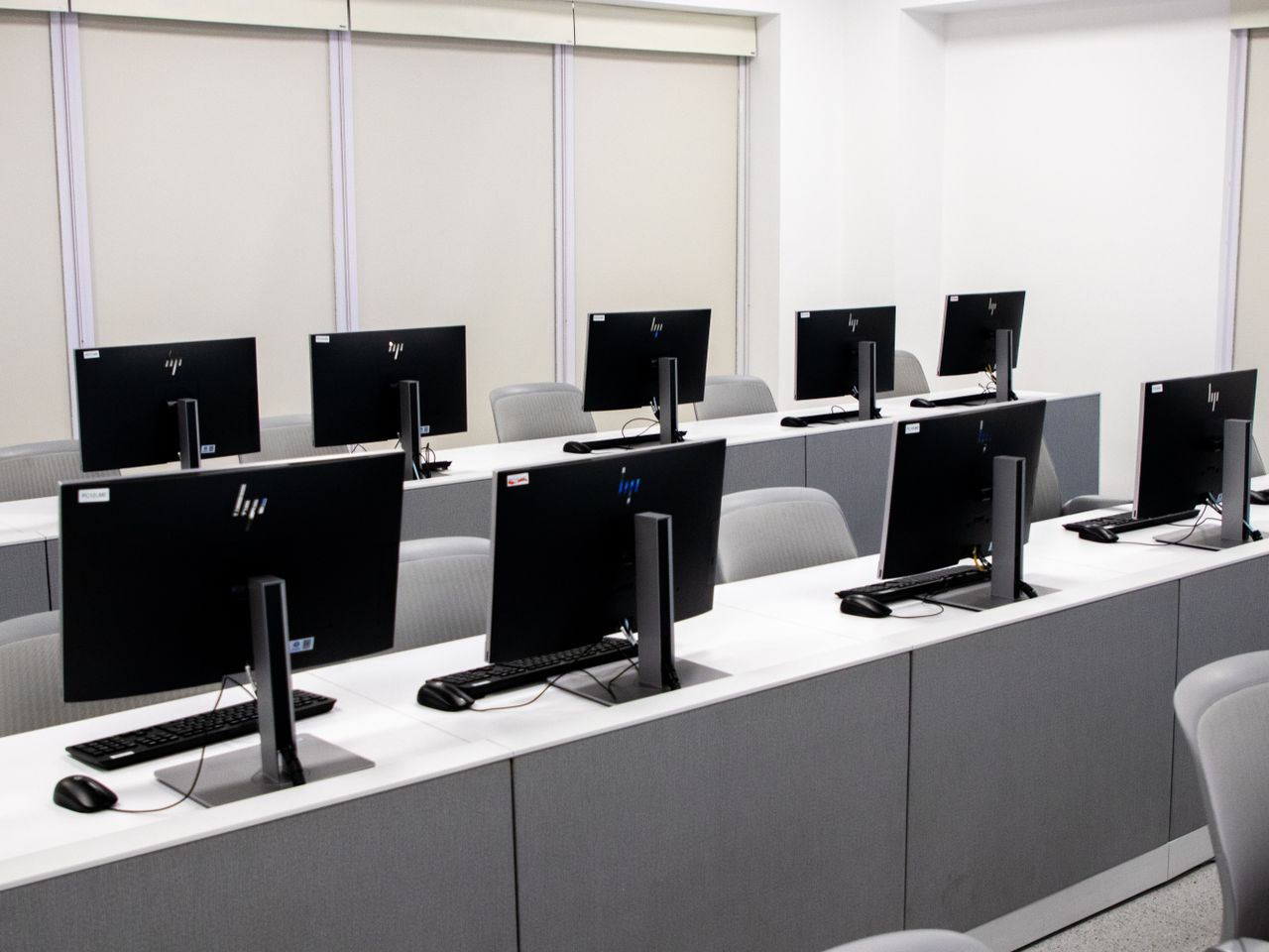 白い机にデスクトップPCが整列したパソコン教室